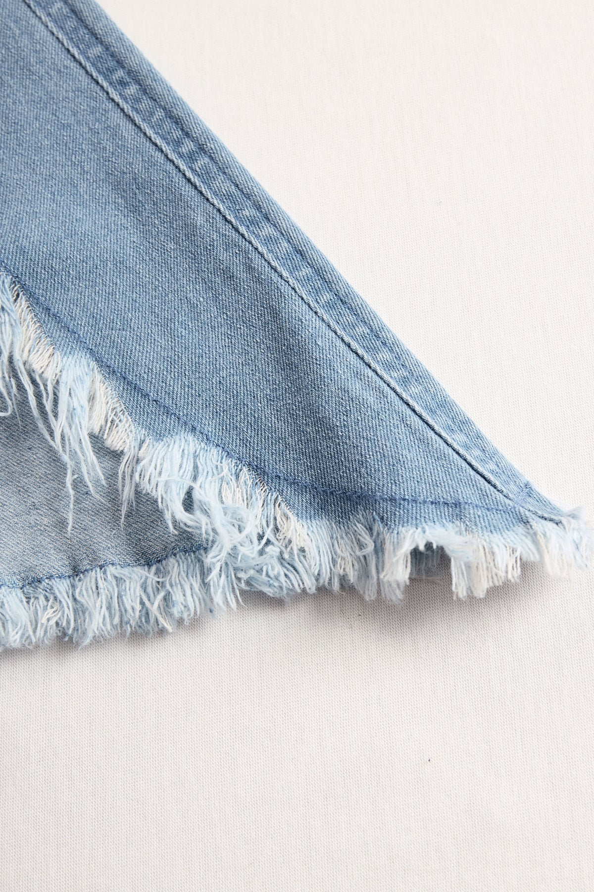 Light blue denim sleeveless raw edge wide-leg jumpsuit for women by Christine Brewer, shown on a hanger.