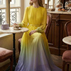Long sleeved high waisted maxi dress by Christine Brewer featuring contrast color gradient, pleated design, belt, and split-joint round neck.