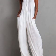 White pleated halter neck wide-leg resort jumpsuit for women by Christine Brewer, featuring stylish pleats and a halter neckline.