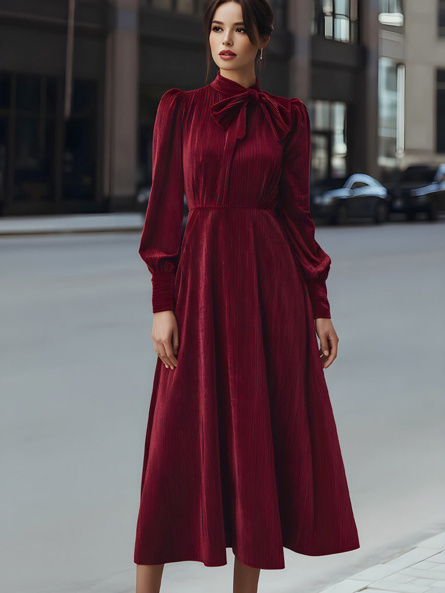 Burgundy velvet pleated bow-neck midi dress by Christine Brewer, featuring a sophisticated cocktail dress design with elegant pleats.