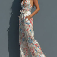White floral satin halter neck jumpsuit with wrap front and wide-leg pants for women by Christine Brewer.
