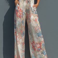 White floral satin halter neck jumpsuit with wide-leg pants for women by Christine Brewer, featuring wrap front design.