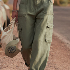 Green multi-pocket cargo trousers for women by Christine Brewer, featuring multiple functional pockets and relaxed fit.