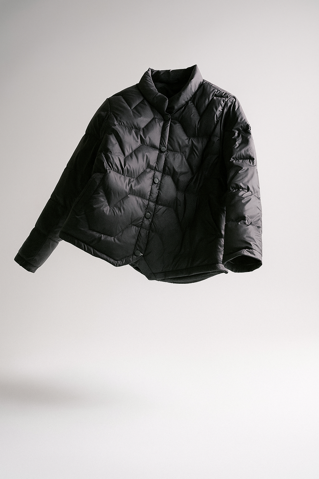 Black quilted puffer jacket for women by Christine Brewer, lightweight short design with a cozy, padded appearance.