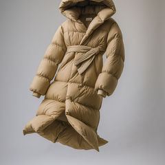 Long belted puffer jacket for women by Christine Brewer, featuring a stylish design and cozy insulation, shown in a sleek black color.
