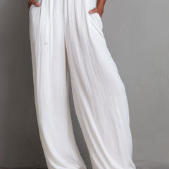 White pleated halter neck wide-leg resort jumpsuit for women, featuring stylish pants from Christine Brewer.