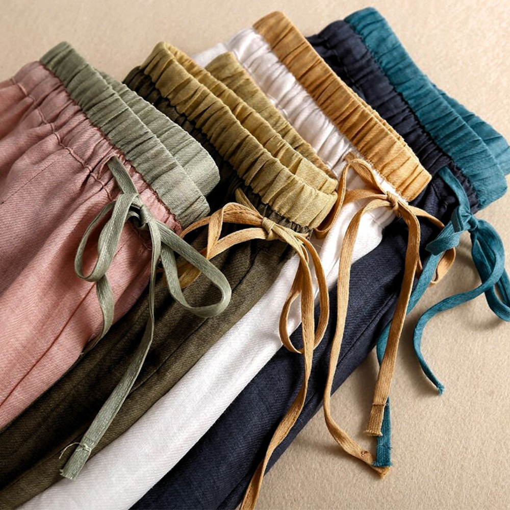 Light beige tapered linen trousers for women by Christine Brewer, featuring a loose pull-on style and relaxed fit.
