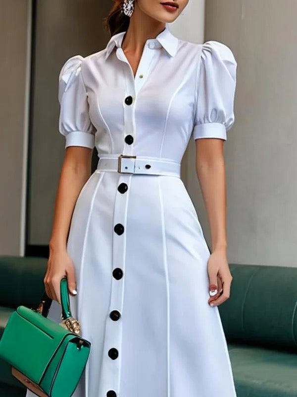White maxi dress with puff short sleeves, belted waist, button details, and lapel collar by Christine Brewer.