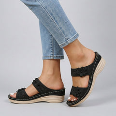 Black floral strap wedge heeled sandals for women by Christine Brewer, featuring comfortable design and stylish floral accents.