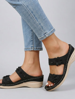 Black floral strap wedge heeled sandals for women by Christine Brewer, featuring comfortable design and stylish floral accents.