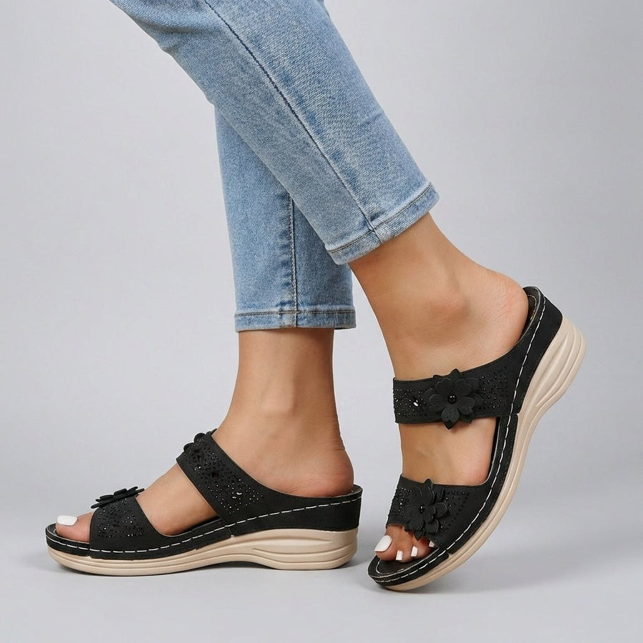 Black floral strap wedge heeled sandals for women by Christine Brewer, featuring comfortable design and stylish floral accents.
