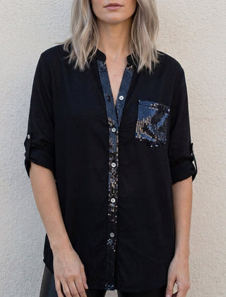 Black women's summer blouse with V-neck, denim fabric, and button front by Christine Brewer, displayed on a hanger.