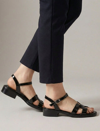Black ankle-length flat sandals with ankle strap and buckle by Christine Brewer, featuring a sleek and comfortable design.