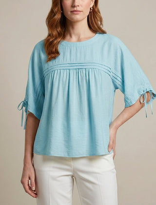Blue linen summer blouse for women by Christine Brewer, flowy and lightweight, shown on a model with short sleeves and relaxed fit.