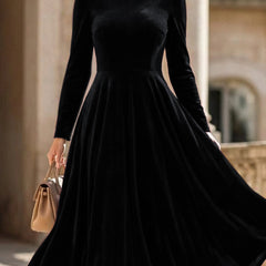 Black velvet round neck long-sleeved dress by Christine Brewer, shown on a hanger with a smooth fabric finish.