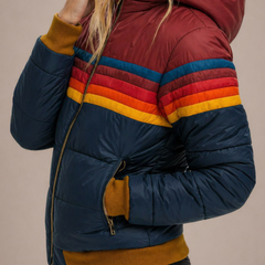 Woman wearing the Clara hooded quilted puffer jacket for women by Christine Brewer, showcasing its quilted design and cozy hood.