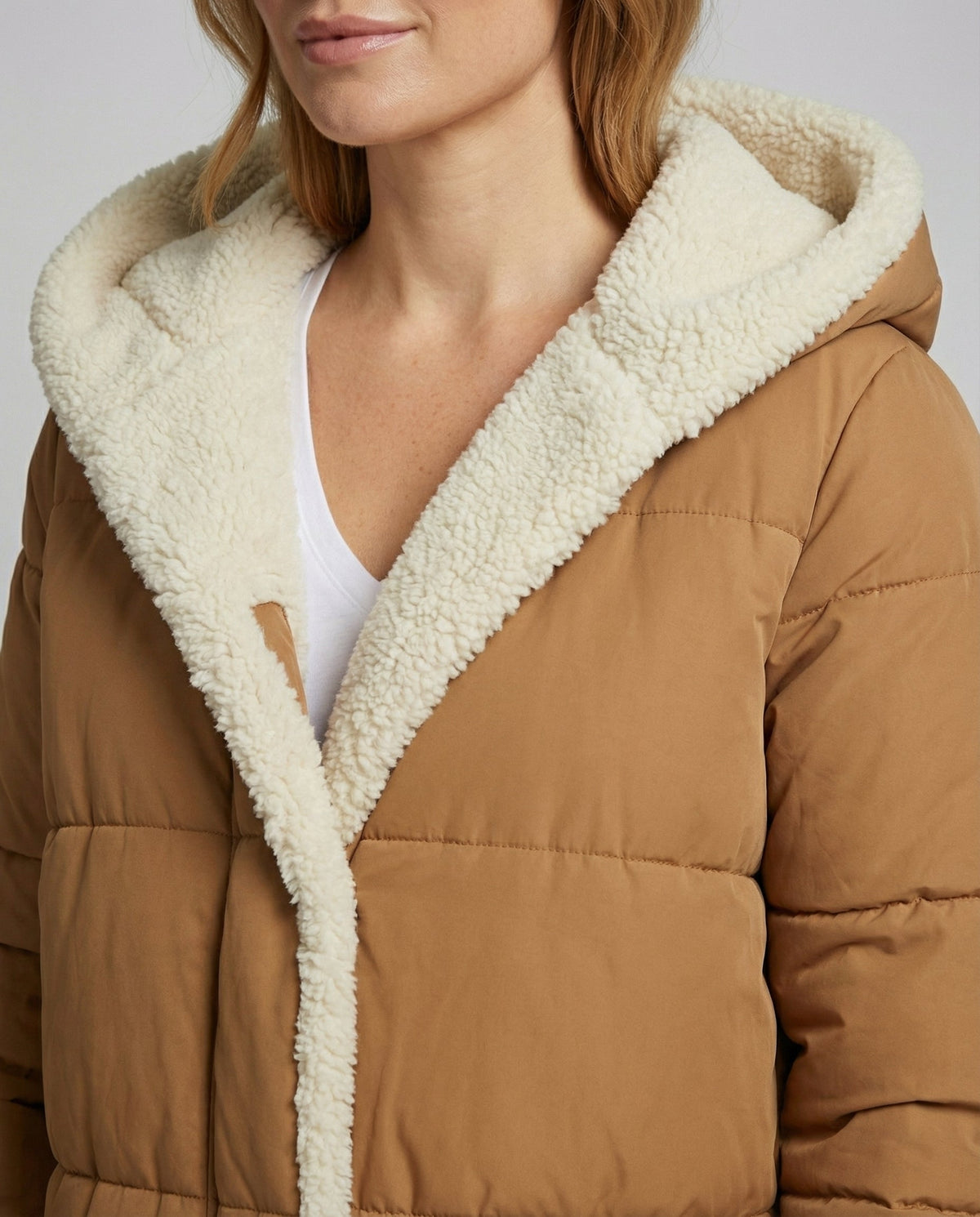 Close-up of a women's Iris long puffer jacket by Christine Brewer, featuring a reversible sherpa fleece detail for winter warmth.