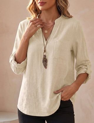 Woman wearing a dusty white V-neck linen summer blouse by Christine Brewer, flowing and lightweight for warm weather.