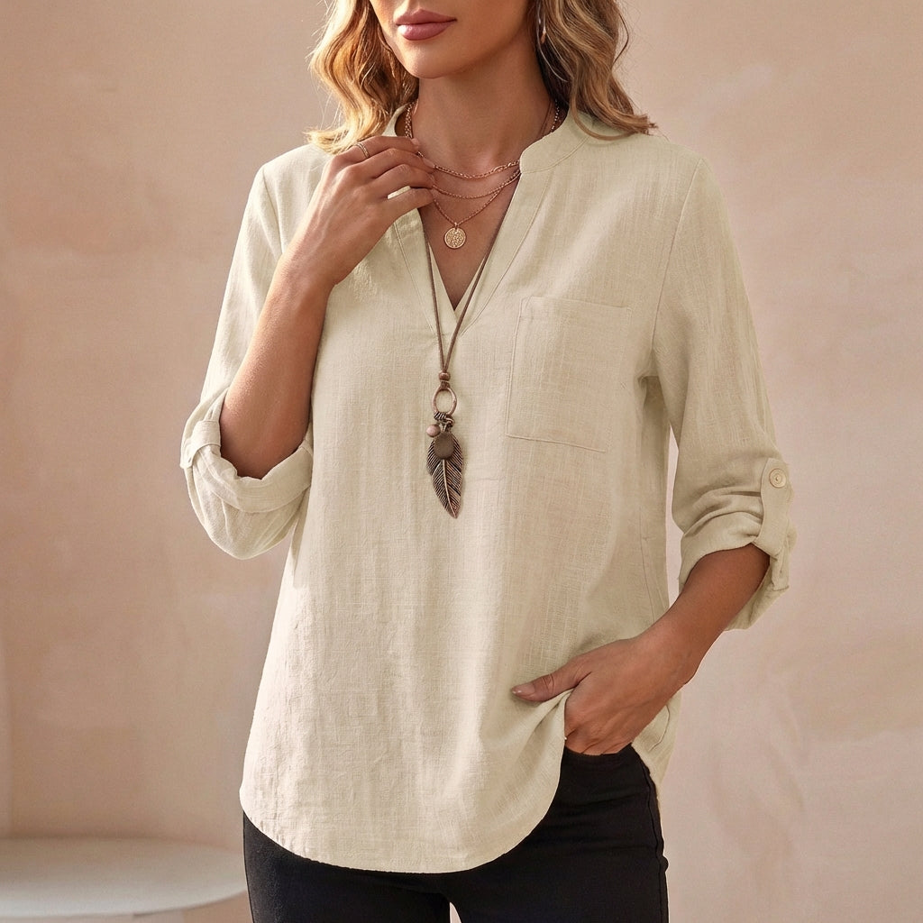 Woman wearing a dusty white V-neck linen summer blouse by Christine Brewer, flowing and lightweight for warm weather.