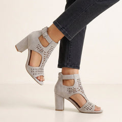 Gray women's cut-out block-heel sandals with ankle buckle by Christine Brewer, showcasing stylish open design and ankle strap detail.