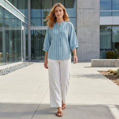 Woman wearing a striped linen summer blouse with button front by Christine Brewer, casual lifestyle shot.