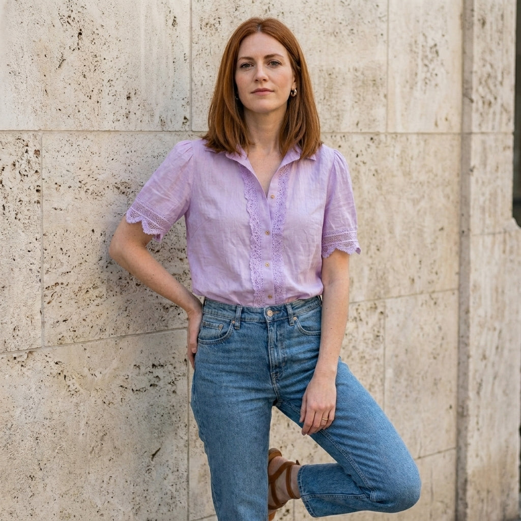 Woman wearing a Christine Brewer summer blouse with a V-neck, short sleeves, and lace detailing, styled for warm weather.