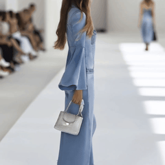 Light blue denim flared long sleeve jumpsuit with wide-leg pants for women by Christine Brewer, shown on a model.