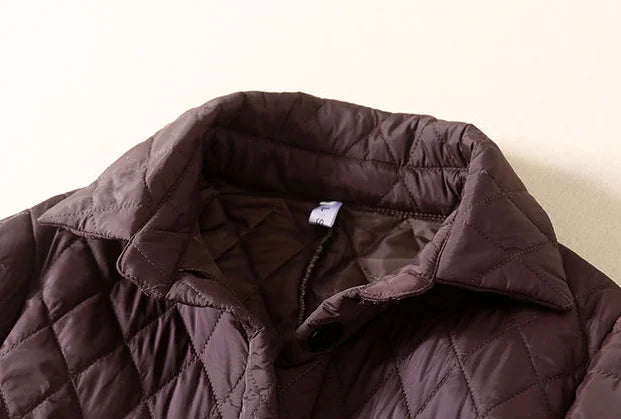 Longline puffer jacket for women by Christine Brewer, featuring a stylish, insulated design with a high collar and quilted texture.