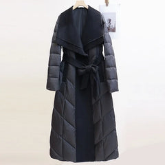 Lily long belted puffer jacket for women by Christine Brewer, featuring a quilted design, belt at waist, and hood for warmth.