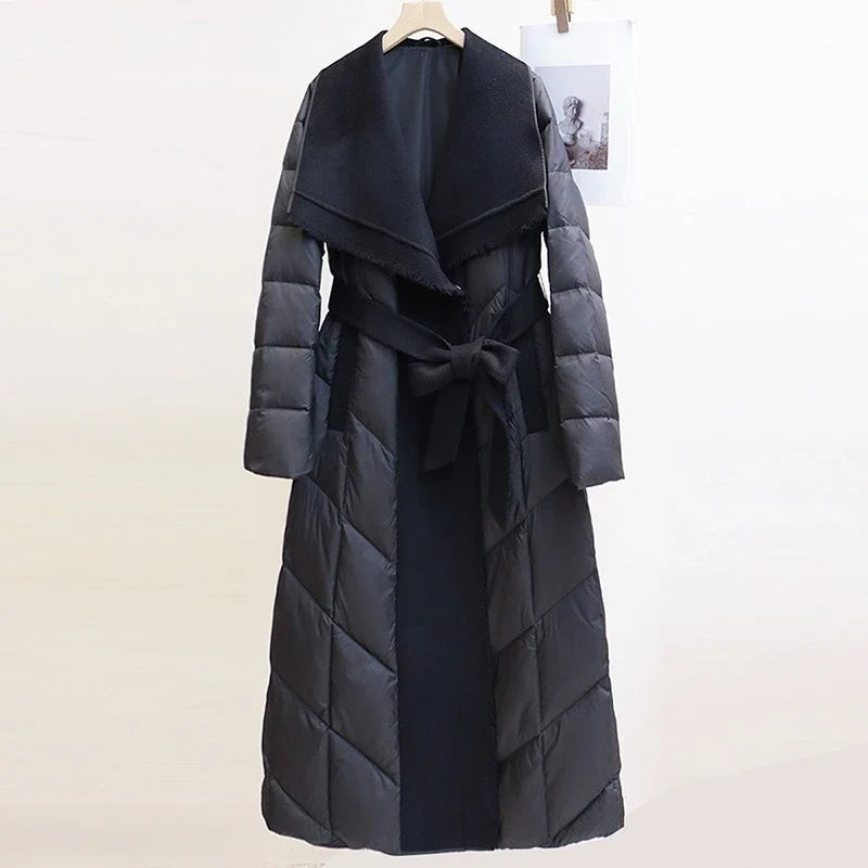 Lily long belted puffer jacket for women by Christine Brewer, featuring a quilted design, belt at waist, and hood for warmth.