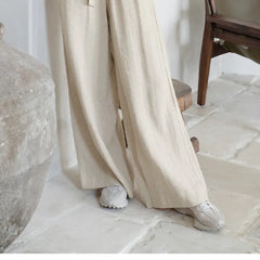 Light beige linen wide-leg trousers for women by Christine Brewer, loose pull-on style with a relaxed fit.