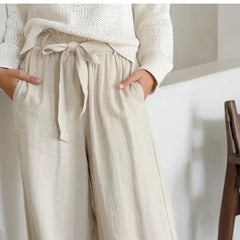Light-colored linen wide-leg women's trousers with a loose pull-on style, featuring a relaxed fit and comfortable waistband.