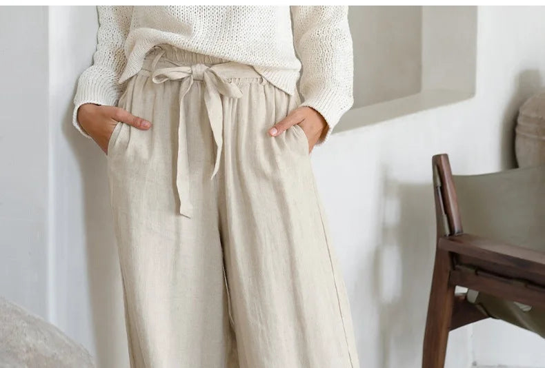 Light-colored linen wide-leg women's trousers with a loose pull-on style, featuring a relaxed fit and comfortable waistband.