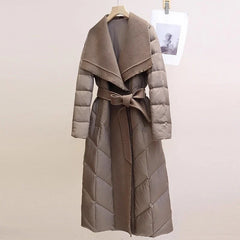 Long belted puffer jacket for women by Christine Brewer, featuring a cozy quilted design and a stylish belt detail.
