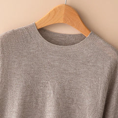 Woman wearing a gray wool sweater by Christine Brewer, featuring a cozy fit and classic design perfect for casual wear.