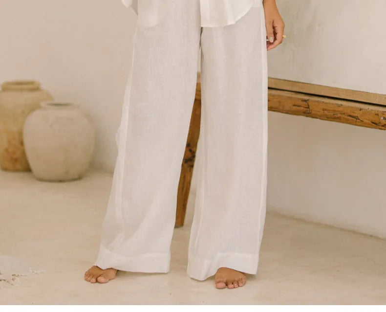 Light beige linen wide-leg trousers for women, loose pull-on style from Christine Brewer, shown laid flat on a white background.