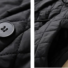 Women’s longline puffer jacket by Christine Brewer, featuring a stylish, insulated design with a high collar and quilted pattern.