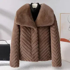Woman wearing the Nova short faux fur coat by Christine Brewer, stylishly layered with a cozy, plush faux fur exterior.