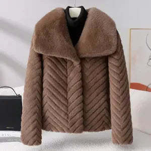 Woman wearing the Nova short faux fur coat by Christine Brewer, stylishly layered with a cozy, plush faux fur exterior.