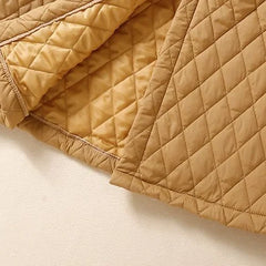 Longline puffer jacket for women by Christine Brewer, featuring a warm, quilted design with a high collar and zipper closure.