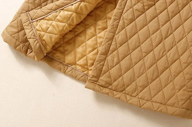 Longline puffer jacket for women by Christine Brewer, featuring a warm, quilted design with a high collar and zipper closure.