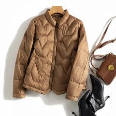 Women’s Aurora short quilted puffer jacket by Christine Brewer, lightweight with a shiny quilted exterior, ideal for cold weather.