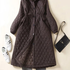Women’s longline puffer jacket by Christine Brewer, Elena style, featuring a sleek, quilted design and high collar for warmth.