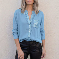 Sky blue women's summer blouse by Christine Brewer featuring a V-neck, denim fabric, and button-front design.