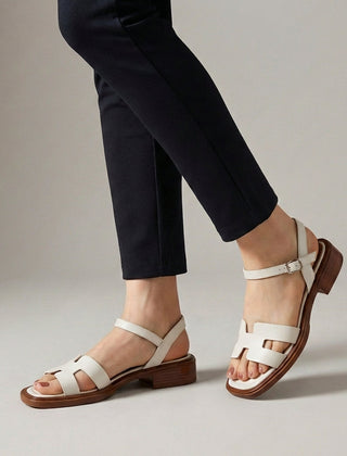 White ankle-length flat sandals with ankle strap and buckle by Christine Brewer, featuring a simple, stylish design.