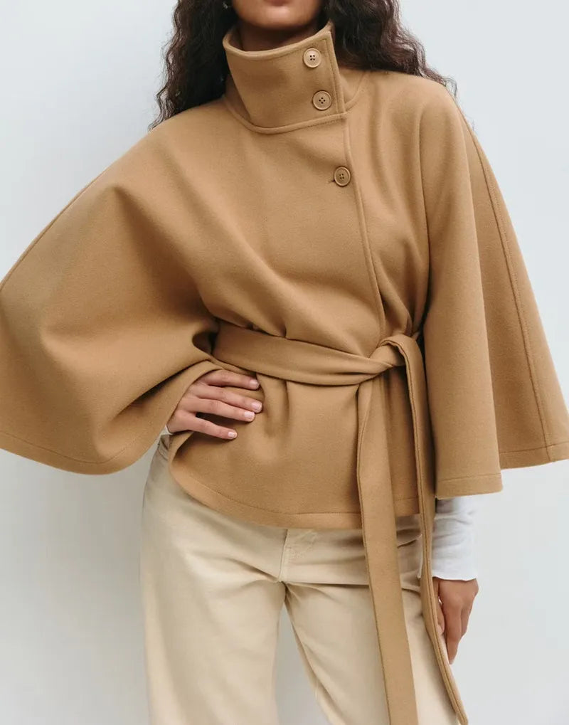 Women’s spring belted high-neck cape coat by Christine Brewer featuring a funnel neck, waist belt, and cape sleeves.