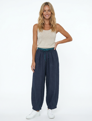 Light beige tapered linen trousers for women, loose pull-on style from Christine Brewer, displayed on a model.