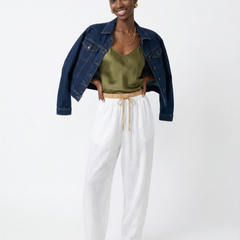 Light beige tapered linen trousers for women by Christine Brewer, featuring a loose, pull-on design and relaxed fit.
