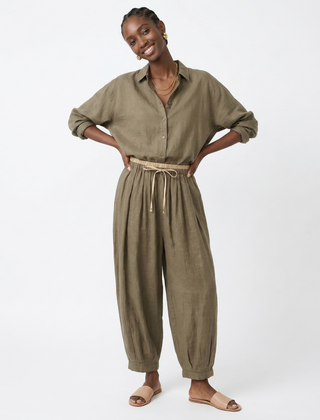 Loose tapered linen trousers for women by Christine Brewer, featuring a relaxed fit and pull-on style in natural linen fabric.