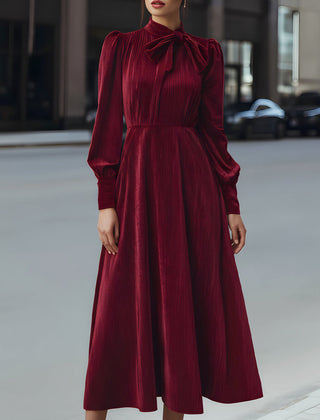 Burgundy velvet pleated bow-neck midi dress by Christine Brewer, elegant cocktail dress with a fitted waist and flowing skirt.